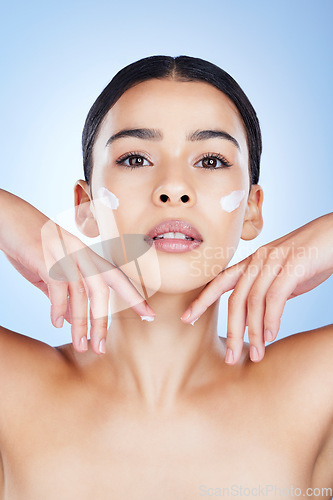 Image of Woman, face and hands in skincare moisturizer, cosmetics or beauty against a blue studio background. Female cheeks with cosmetic product, lotion or cream for facial treatment or self love or care