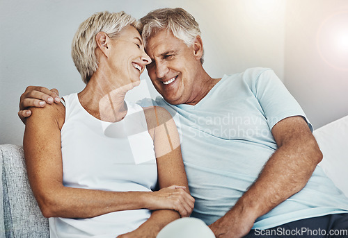 Image of Love, laughing and retirement with a senior couple sitting in the living room of their home together. Happy, smile or relax with a mature man and woman joking while bonding on the couch in a house