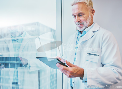 Image of Tablet, doctor and medical professional doing online health or telehealth connected to internet, web or wifi in an office building. GP, senior and elderly healthcare worker working by window typing