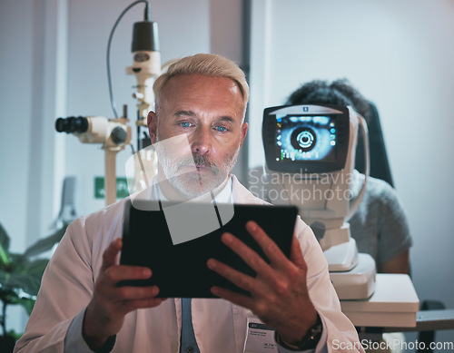 Image of Digital tablet, optometry and man in a clinic doing optic research during eye care consultation. Ophthalmology, healthcare and senior male optometrist working on mobile device while doing vision test