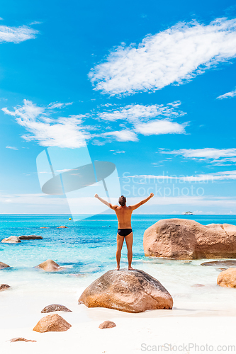 Image of Happy man on the beautiful sandy beach rising hands to the sky on summer vacations on Seychelles. Freedom and happiness concept.