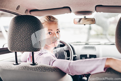 Image of Female driver looking back while reversing in car.