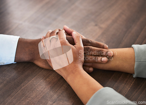 Image of Support, help and couple holding hands for trust, empathy and unity in crisis, cancer or bad news. Solidarity, care and man and woman together on table for praying, comfort and prayer, hope or love.