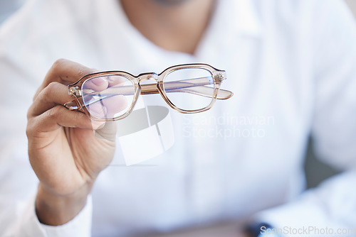 Image of Glasses, optometry and hand of optometrist holding spectacles, eyewear or specs for ophthalmology in an office. Person, eye care and doctor or professional with a vision frame by medical employee