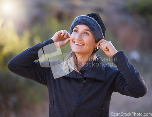 Image of Music, earphones and woman hiking in nature outdoors for health, exercise and fitness. Winter sports, thinking and happy female hiker streaming radio, podcast or audio after training in forest park.