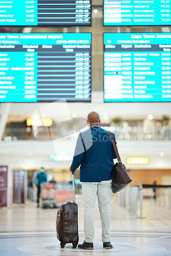 Image of Black man in airport, flight schedule display and waiting in terminal for international business trip from back. Visa, travel and luggage, businessman checking international destination boarding time