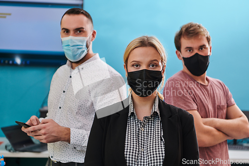 Image of A group of colleagues stand ingin a robotics laboratory, arms crossed, wearing protective masks, symbolizing their teamwork and commitment to technological innovation and scientific research.