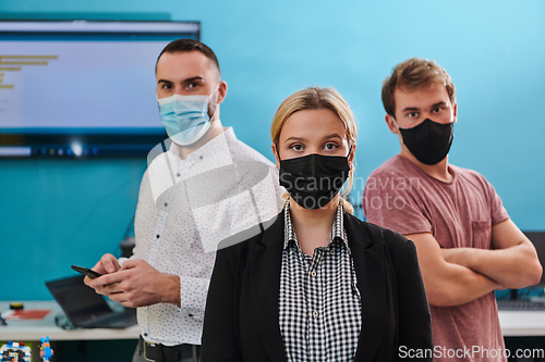 Image of A group of colleagues stand ingin a robotics laboratory, arms crossed, wearing protective masks, symbolizing their teamwork and commitment to technological innovation and scientific research.