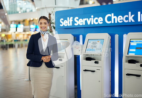 Image of Woman, passenger assistant and airport by self service check in station for information, help or FAQ. Portrait of happy female services agent standing ready to assist people in travel destination