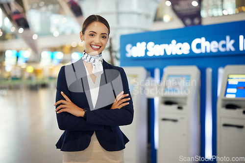 Image of Woman, passenger assistant and arms crossed at airport by self service check in station for information, help or FAQ. Portrait of happy female services agent standing ready to assist people in travel