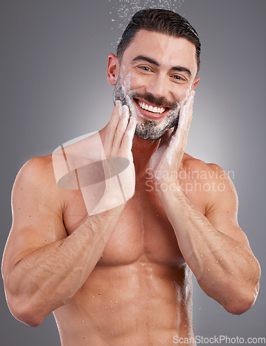 Image of Soap, beard and portrait of a man in the shower isolated on a grey studio background. Skincare, cleaning and model washing facial hair for grooming, hygiene and morning routine on a backdrop