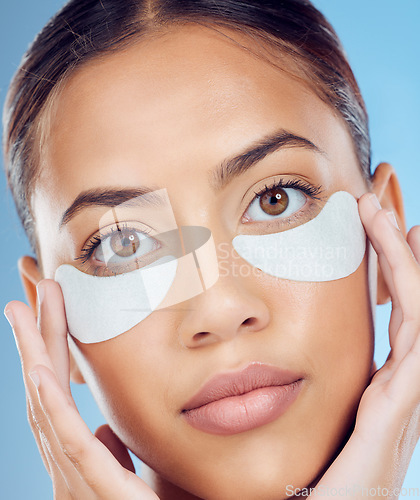 Image of Face, skincare and woman with eye patches in studio isolated on a blue background. Dermatology, portrait and female model with facial cosmetics or pad product for healthy skin, wellness and beauty.