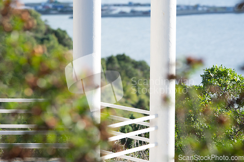 Image of White columns of the gazebo against the backdrop of forest and sea