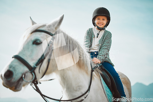Image of Ranch, happy and girl child on a horse to practice riding for a championship, competition or race. Happiness, animal and kid with smile practicing to ride a pony pet on a field or farm in countryside