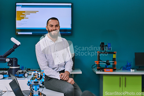 Image of A bearded man in a modern robotics laboratory, immersed in research and surrounded by advanced technology and equipment.