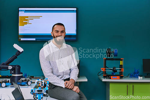 Image of A bearded man in a modern robotics laboratory, immersed in research and surrounded by advanced technology and equipment.