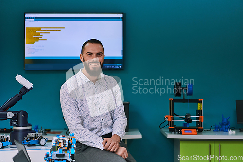 Image of A bearded man in a modern robotics laboratory, immersed in research and surrounded by advanced technology and equipment.