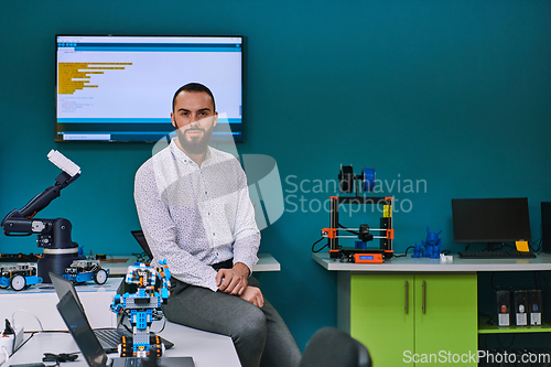 Image of A bearded man in a modern robotics laboratory, immersed in research and surrounded by advanced technology and equipment.