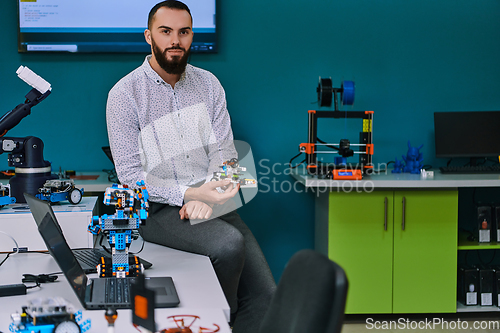 Image of A bearded man in a modern robotics laboratory, immersed in research and surrounded by advanced technology and equipment.