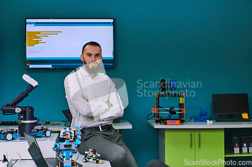 Image of A bearded man in a modern robotics laboratory, immersed in research and surrounded by advanced technology and equipment.