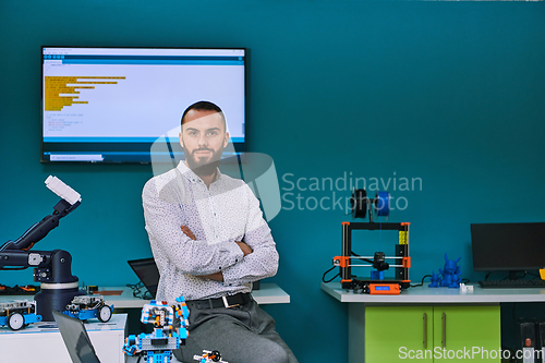 Image of A bearded man in a modern robotics laboratory, immersed in research and surrounded by advanced technology and equipment.