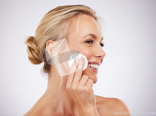 Image of Face, cotton and skincare with a mature woman in studio on a gray background cleaning her skin for exfoliation. Relax, luxury and product with a female using a pad to cleanse her pores for beauty