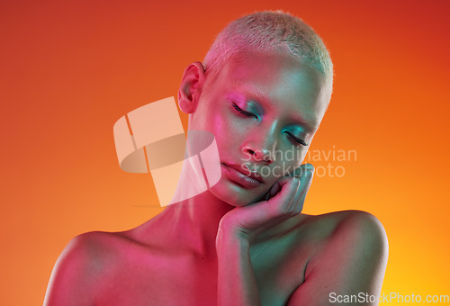 Image of Skincare, beauty and neon cosmetics, woman with face makeup and light in creative advertising on orange background. Cyberpunk, product placement and model isolated in future mockup space in studio.