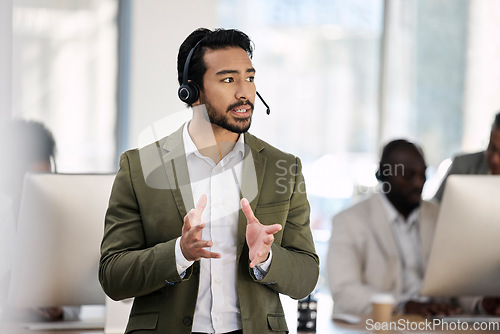 Image of Call center, serious and consulting with man in office for customer support, telemarketing and advisory. Help desk, team leader and contact us with employee listening for communication, sales and crm