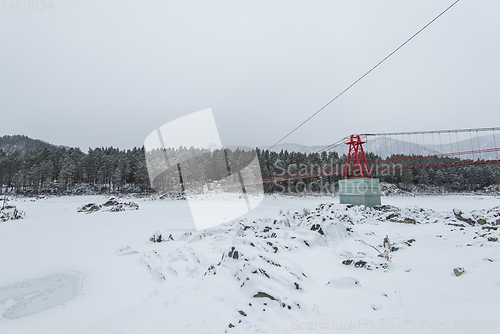 Image of Suspension hanging bridge above winter frozen river