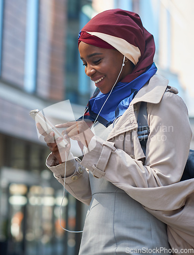 Image of Black woman, phone and smile listening to music in the city for communication, social media or chat. African American and independent girl typing on smartphone with 5G connection, app and earphones