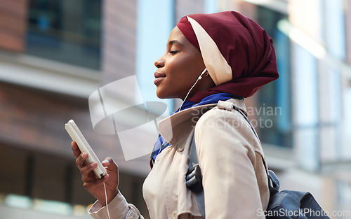 Image of Happy, music and phone with black woman in city for relax, streaming and social media. Independent, internet and hijab radio with muslim girl listening to earphones for podcast, online and digital