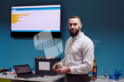 Image of A bearded man in a modern robotics laboratory, immersed in research and surrounded by advanced technology and equipment.