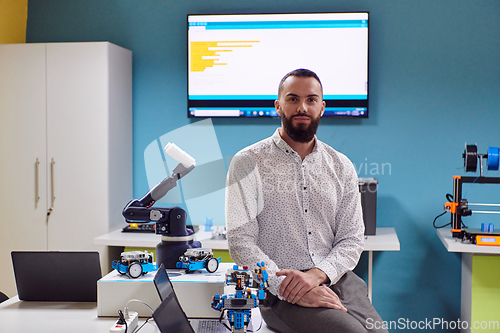 Image of A bearded man in a modern robotics laboratory, immersed in research and surrounded by advanced technology and equipment.