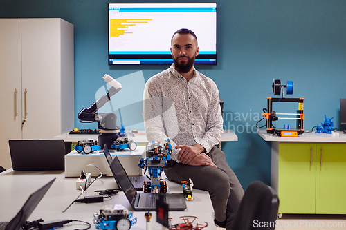 Image of A bearded man in a modern robotics laboratory, immersed in research and surrounded by advanced technology and equipment.