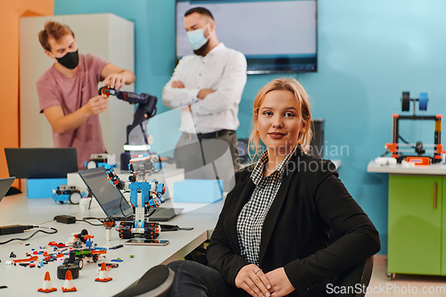 Image of A woman sitting in a laboratory while her colleagues test a new robotic invention in the background