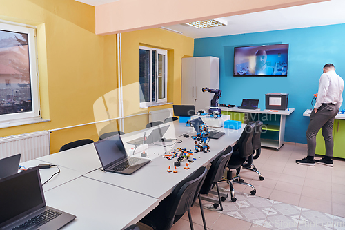 Image of A bearded man in a modern robotics laboratory, immersed in research and surrounded by advanced technology and equipment.