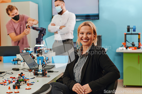 Image of A woman sitting in a laboratory while her colleagues test a new robotic invention in the background