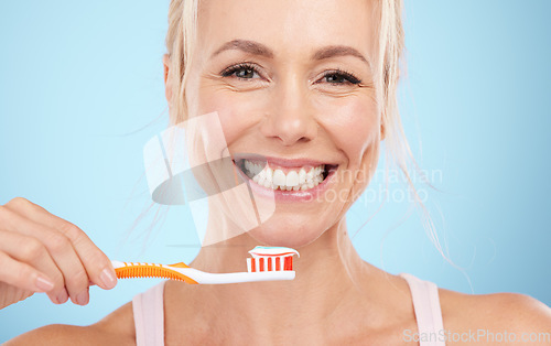 Image of Portrait, mature woman and brushing teeth isolated on blue background in dental, mouth or orthodontics healthcare. Beauty model or happy person face for toothbrush product and toothpaste in studio