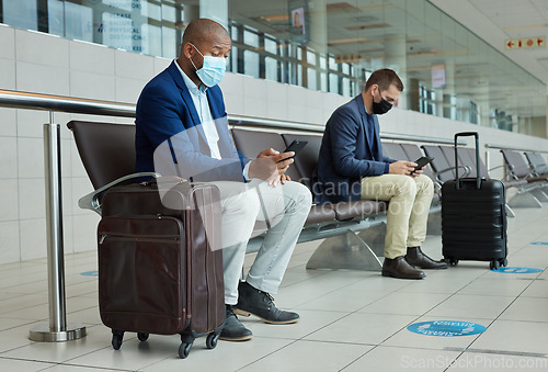 Image of Social distance, suitcase and businessmen waiting in the airport and networking with cellphone. Face mask, luggage and professional male employees sitting with travel restrictions browsing on a phone