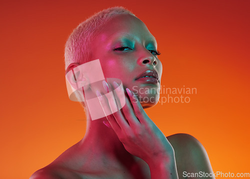 Image of Skincare, beauty and portrait woman with neon face makeup and light in creative advertising on orange background. Cyberpunk, art and model isolated for skin care and futuristic mockup space in studio