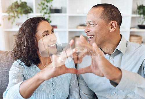 Image of Hand, heart and mature couple with love on a sofa for bonding, romance and happy in a living room. Hands, emoji and romantic older man with woman, happy and smile while enjoying retirement lifestyle