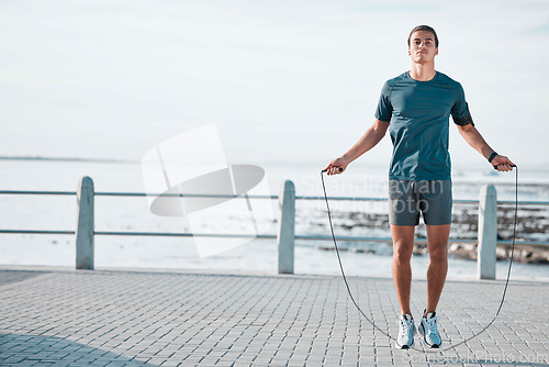 Image of Skipping rope, mockup and man training by the beach for his outdoor morning exercise, workout and fitness routine. Athlete, cardio and male jump by the ocean or sea for wellness lifestyle