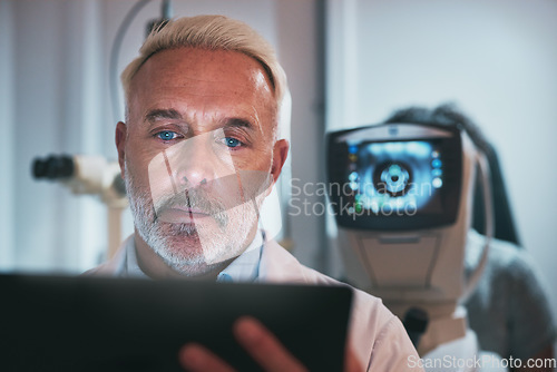 Image of Optometry, healthcare and optometrist doing a eye test in the clinic for eyecare or vision. Medical, tablet and senior male ophthalmologist doing optic research on a mobile device in a optical store.