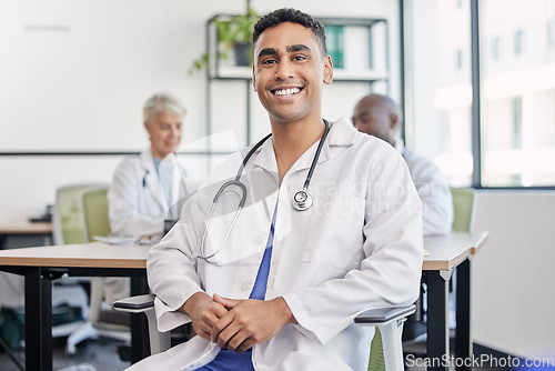 Image of Young doctor, man and portrait at hospital desk with smile for healthcare, planning and teamwork. Professional leader, doctors and expert in health, wellness and happy in clinic with group at table