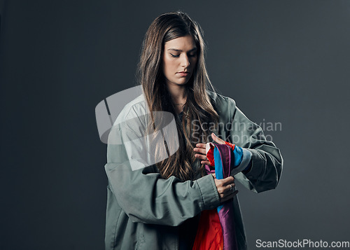 Image of Protest, LGBTQ and woman with flag in studio wrapping it on hand for human rights and equality. Empowerment, sexuality and female political activist with bisexual material isolated by gray background