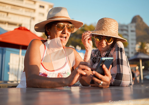 Image of Friends, senior women and phone for internet, search or browse social media, break or summer, retirement or holiday. Elderly people and ladies bond for profile picture or meme at outdoor restaurant