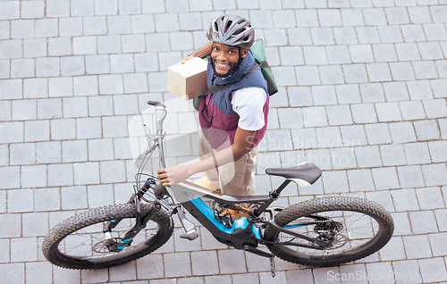 Image of Black man, delivery bike and street portrait from top view for logistics, cargo and happy for job. Young african person, bicycle and shipping service with box package, helmet and safety in metro