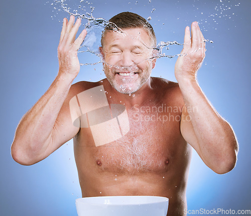 Image of Skincare, senior man and water splash with basin, dermatology and guy with blue studio background. Face detox, mature male and old gentleman with clear liquid, hygiene or aqua for freshness with bowl