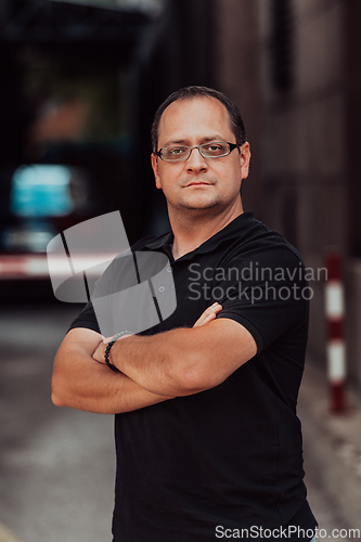 Image of A successful businessman with crossed arms, posing outdoors