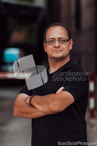 Image of A successful businessman with crossed arms, posing outdoors